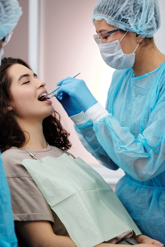 Dentist in protective gear examining a womans teeth during a dental clinic visit.