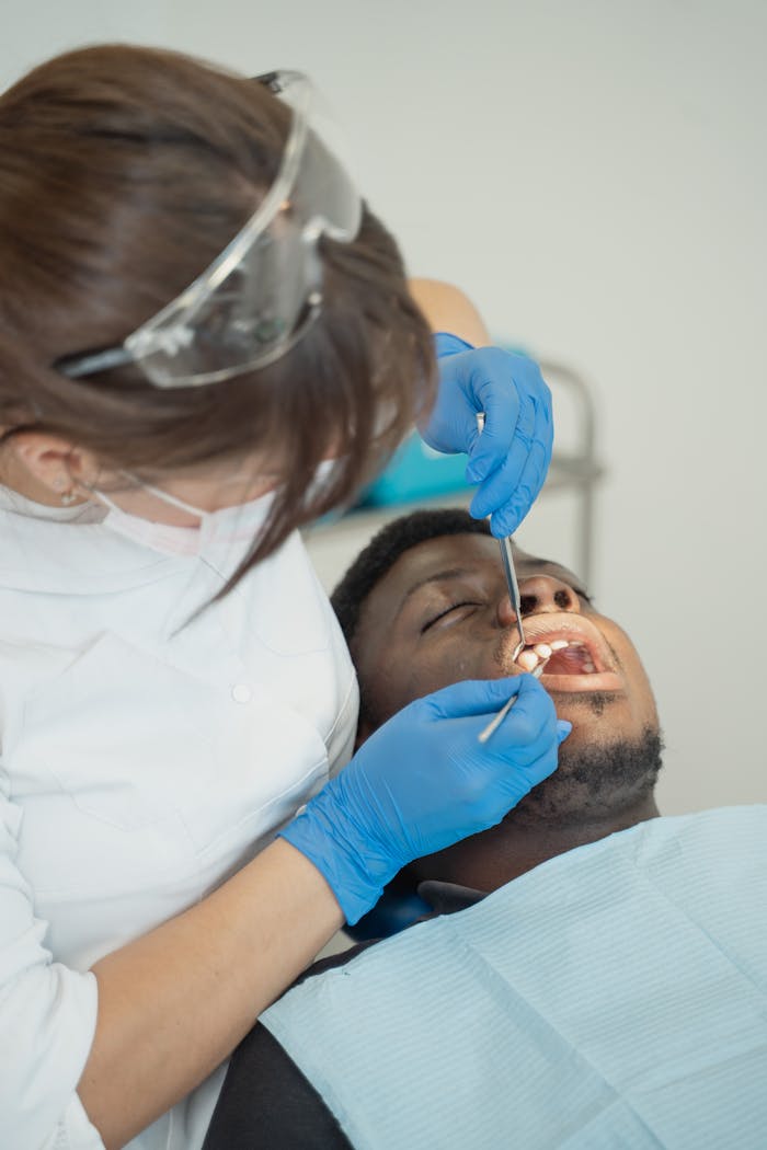 Dentist examining patients teeth using dental tools in a clinic setting.